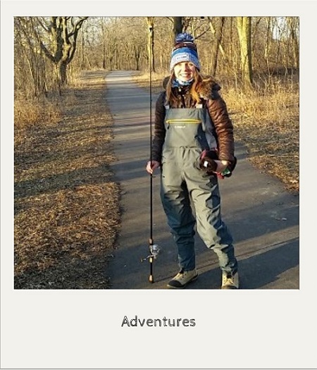 photo of katie richmond dressed in fly fishing gear and standing on a paved path with trees in background